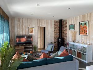 a living room with a blue couch and a television at EVASION BASSIN La Villa Albatros in Lège