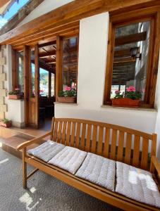 Hostal Toscana في اوخيدو: مقعد خشبي جالس أمام مبنى به نوافذ