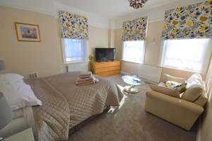 a bedroom with a bed and a chair and a tv at Captain Wills Apartment in Filey