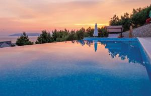 a blue swimming pool with a bench and the sunset at Luxury villa with heated pool, jacuzzi and sauna in Makarska