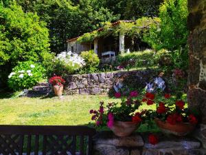 a garden with flowers and a stone wall at O Lughar Darriba Fogar Natural in Gallardo