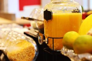 a jar of orange juice sitting next to some apples at Ibis Guaxupe in Guaxupé