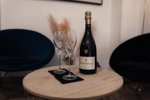 a bottle of wine and two wine glasses on a table at Suite 50 Nuances avec Jacuzzi Privatif Dark Room Perpignan in Villeneuve-de-la-Raho