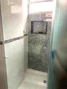 een badkamer met een douche en een betegelde muur bij Daniel Cozy Flat Copa 1 - à 5min da praia in Rio de Janeiro