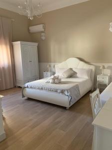 a bedroom with a white bed and wooden floors at B&B Palma Salentina in Lizzano