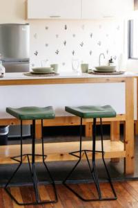 a kitchen with a counter with two green stools at Coyote Lofts-Estacion Federal in Tijuana