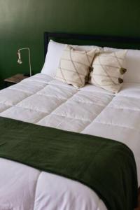 a white bed with a green blanket and pillows at Coyote Lofts-Estacion Federal in Tijuana