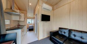 a living room with a leather couch and a kitchen at Fox Glacier TOP 10 Holiday Park & Motels in Fox Glacier