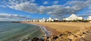 Blick auf einen Strand mit Gebäuden im Hintergrund in der Unterkunft Varandas de Carteia in Quarteira