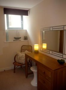 a bathroom with a desk with a mirror and a window at Old Templars Cottage in Spittal
