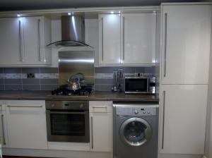 a kitchen with white cabinets and a washing machine at Old Templars Cottage in Spittal