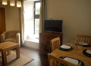 een woonkamer met een tafel en een televisie bij Old Templars Cottage in Spittal