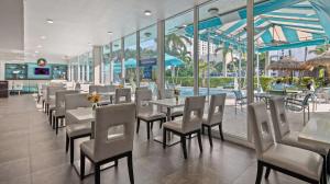 a restaurant with tables and chairs and a pool at Best Western Plus Oceanside Inn in Fort Lauderdale