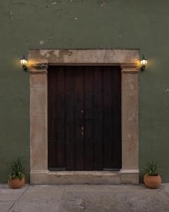 une porte en bois avec deux plantes devant un bâtiment dans l'établissement Narrativ Lofts - Serena - Beautiful Colonial Suite, à Campeche