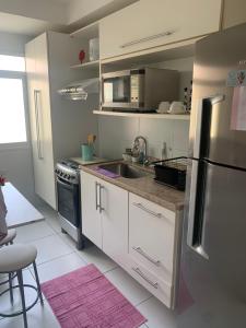 a kitchen with white cabinets and a stainless steel refrigerator at Apartamento em Maceió - JTR México in Maceió