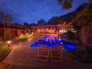 a house with a swimming pool with two chairs next to it at Pousada Meraki in Serra do Cipo