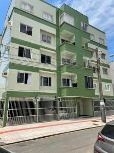 un edificio verde sul lato di una strada di Apartamento amplo e completo no centro Balneário Camboriú a Balneário Camboriú