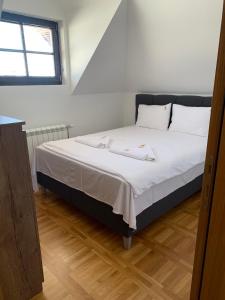 a bedroom with a bed with white sheets and a window at Mountain Villa Zlatibor in Zlatibor