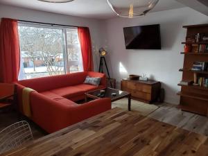 a living room with a red couch and a window at The Orange Suite 2BR Vintage Vibe, Chefs Kitchen in London