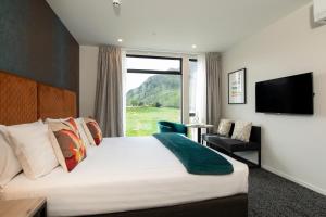 クイーンズタウンにあるQuest Queenstown Apartments Remarkables Parkのベッドと大きな窓があるホテルの部屋