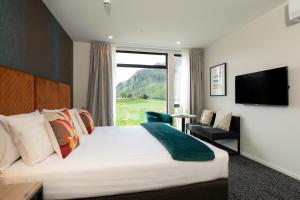 a hotel room with a bed and a large window at Quest Queenstown Apartments Remarkables Park in Queenstown