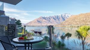 a table with wine glasses on a balcony overlooking a lake at Alpine Lakeside Studio in Queenstown