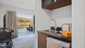 a kitchen with a sink and a view of a patio at Alpine Lakeside Studio in Queenstown