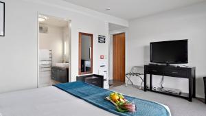 Habitación con 1 cama con TV y un bol de fruta en Alpine Lakeside Studio, en Queenstown
