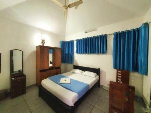 a bedroom with a bed with blue curtains and a mirror at Vintage Garden Resort in Sultan Bathery