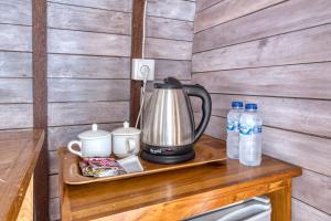 a tea kettle on a tray on a table with water bottles at Megaland Bungalow in Nusa Penida