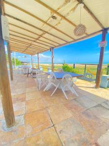 eine Terrasse mit einem Tisch, Stühlen und Meerblick in der Unterkunft Pousada e Restaurante Sombra dos Coqueiros in Trairi