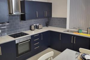 a kitchen with blue cabinets and a sink at Kepler Residence Modern 4 Bedroom Property 1 mile from Leeds Centre in Leeds
