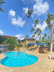 a person in the swimming pool at a resort at Pousada e Restaurante Sombra dos Coqueiros in Trairi