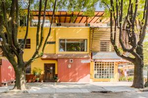 a yellow and red house with trees in front of it at Casa Anzures S in Mexico City