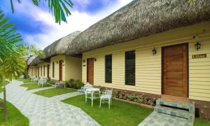 a resort with tables and chairs and a thatched roof at RedDoorz @ Afamosa Villas Resort Ilocos Sur in Cabanglotan