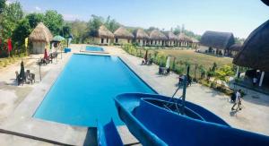 a swimming pool at a resort with thatched huts at RedDoorz @ Afamosa Villas Resort Ilocos Sur in Cabanglotan