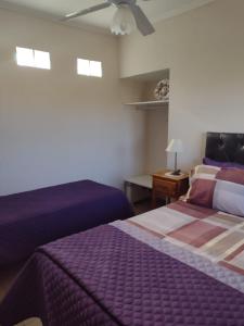 een slaapkamer met 2 bedden en een plafondventilator bij Cabañas Y Departamentos Bettylu in Villa Cura Brochero