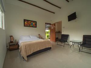 a bedroom with a bed and two chairs and a television at San Juan de los Guayabos in Guaduas