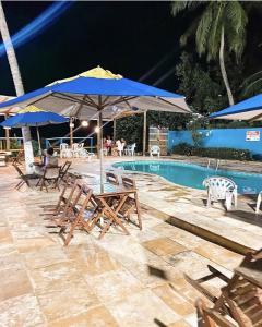 een groep stoelen en parasols naast een zwembad bij Pousada e Restaurante Sombra dos Coqueiros in Trairi