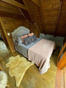 a bedroom with a bed with pillows and a rug at Chalé de Pedra Recanto Verde dos Canyons in Praia Grande