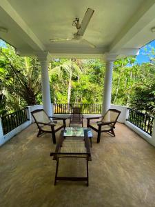 un porche con 4 sillas y una mesa. en Shirani nature palace, en Weligama