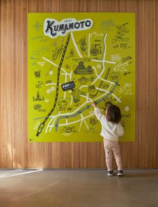 uma criança está apontando para um mapa em uma parede em FAV HOTEL KUMAMOTO em Kumamoto