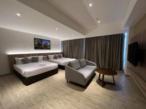 ein Hotelzimmer mit 2 Betten und einem Sofa in der Unterkunft Amverton Cove Golf & Island Resort in Banting