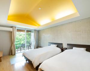 2 camas en una habitación con techo amarillo en Asahinoyado Shidakaji en Nanjo