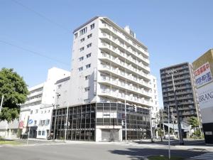 a tall white building on a street corner at Lestel Maru in Sapporo