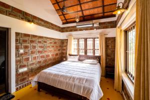 1 dormitorio con cama y pared de ladrillo en Cynefin, Pet-friendly 2br by the backwaters by Roamhome en Murinjupuzha
