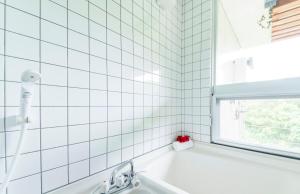 a white tiled bathroom with a sink and a window at Asahinoyado Shidakaji in Nanjo +15 photos