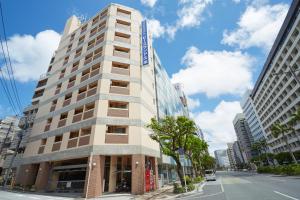 a tall white building on a city street at Peace Land Kume in Naha