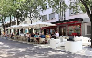 Un groupe de personnes assises à des tables avec des parapluies dans l'établissement Hôtel Elite, à Sion