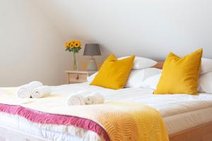 a bed with yellow pillows and towels on it at Fiastyúk Udvarház in Csór